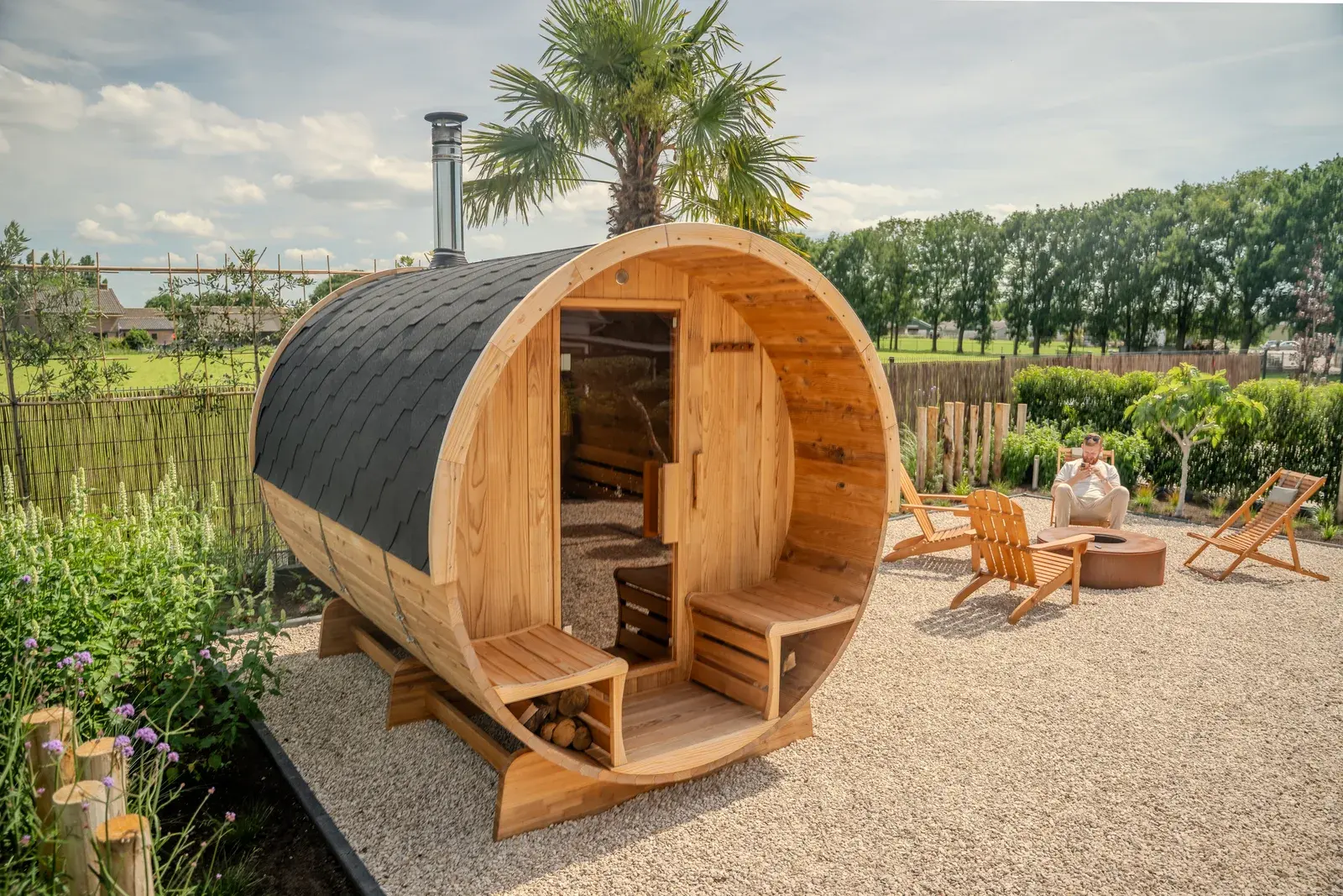 Open barrel sauna in the garden with wooden benches and a fire bowl