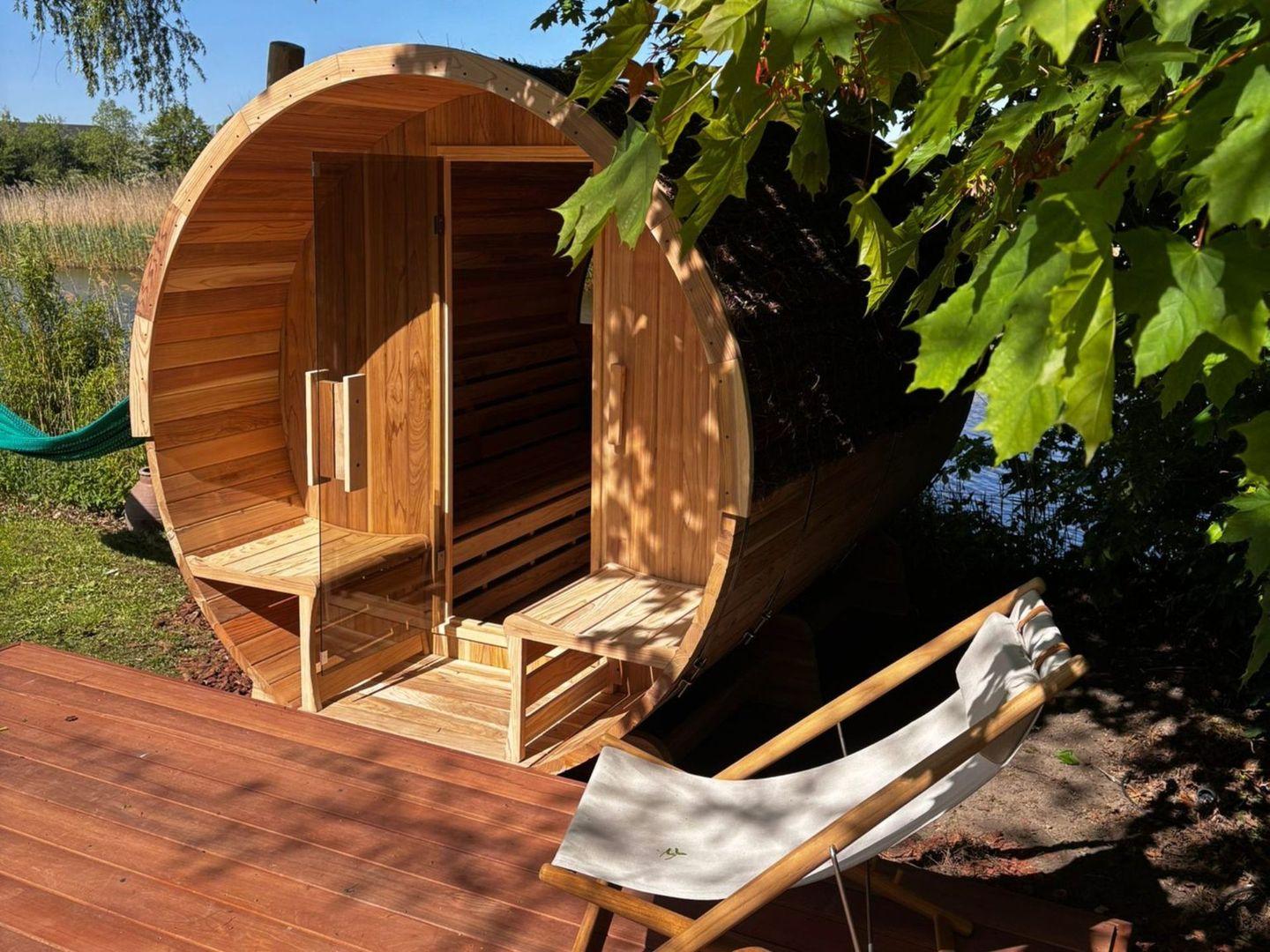 Barrelsauna met open deur op een vlonder aan het water