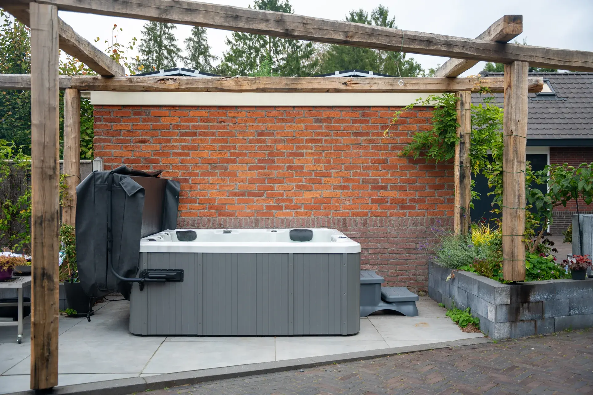 De Goldline spa bij de bakstenen muur en houten pergola