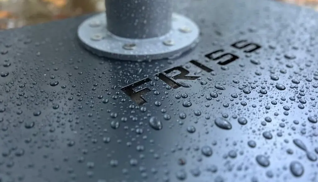 Detail van de Friss-voetplaat met ingegraveerd logo en regendruppels
