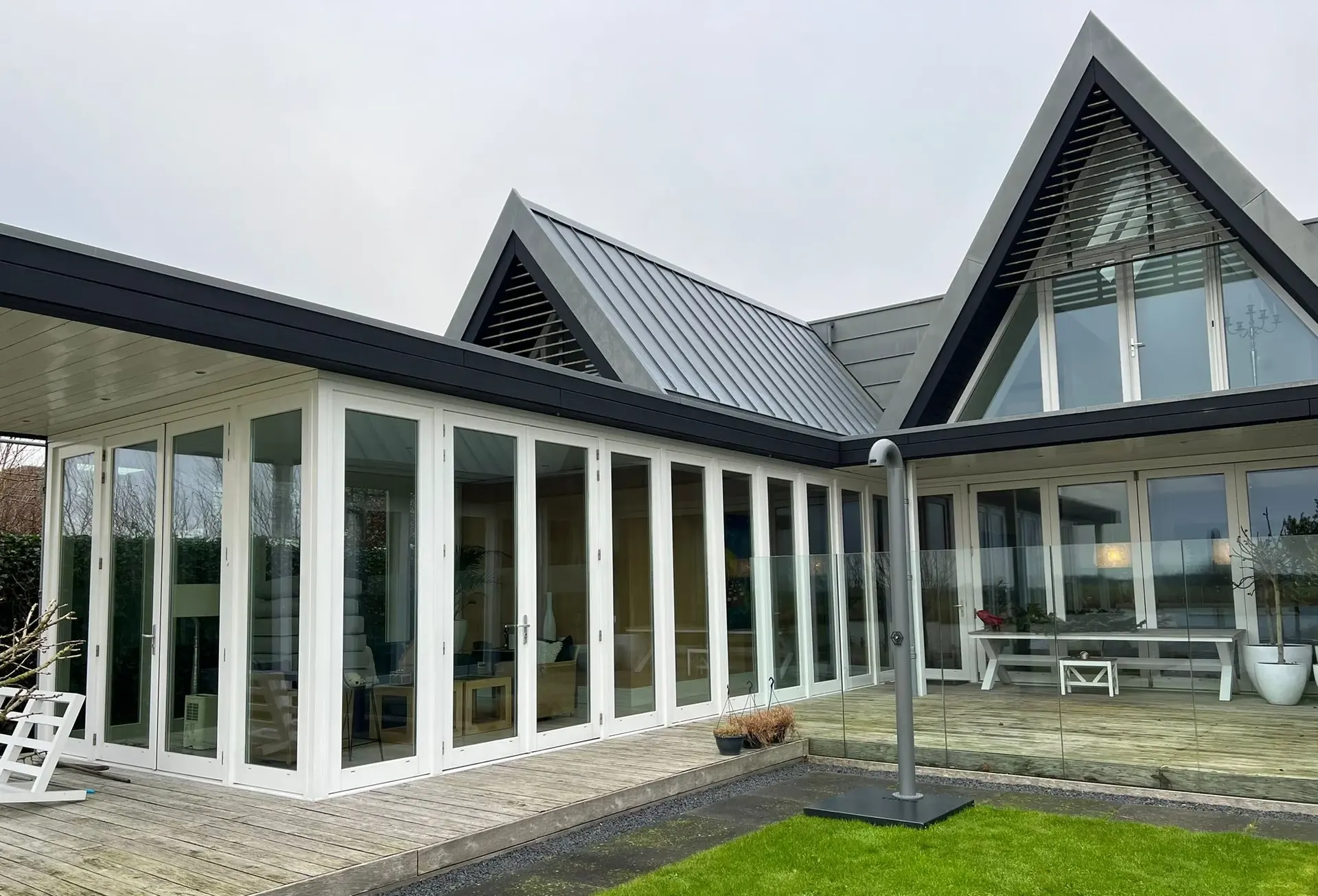 Friss buitendouche op het houten terras van een moderne villa